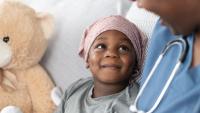 child with lymphoma smiling and looking up at doctor